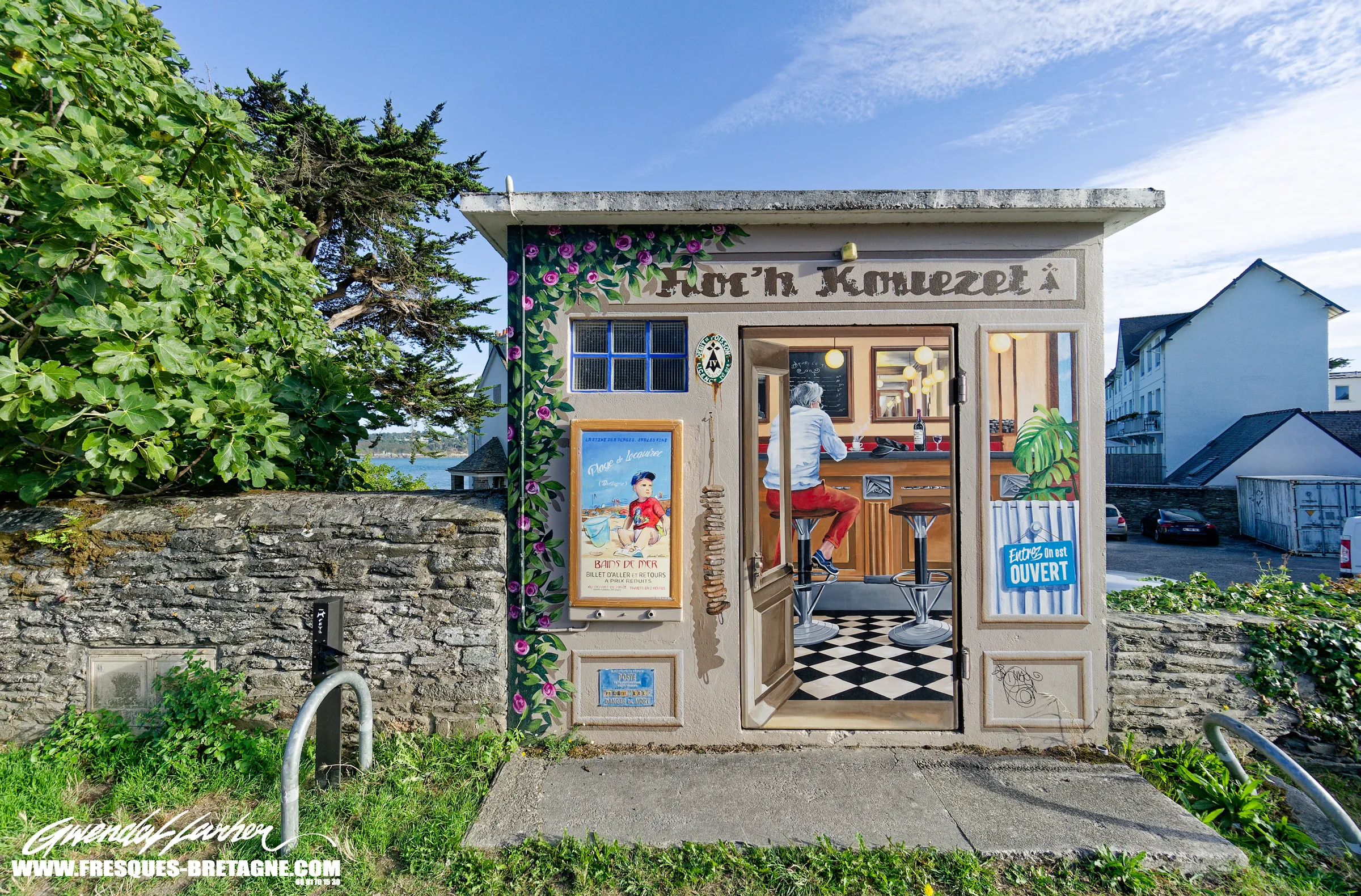 Transformateur électrique transformé en faux bistrot breton, porte ouverte sur un comptoir, affiche de plage et rosiers grimpants, trompe-l'œil de façade à Locquirec